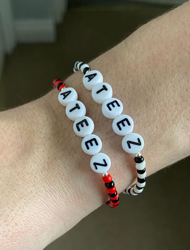 two bracelets with letters on them sitting on someone's arm