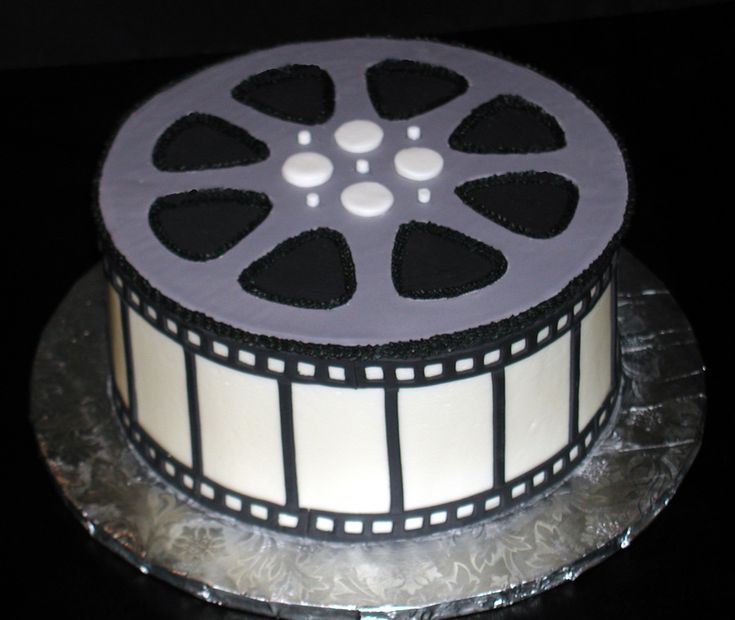 a film reel cake with frosting and black icing on a silver platter