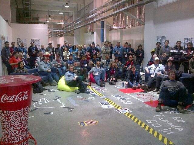 a group of people sitting on the floor in front of a coca - cola machine