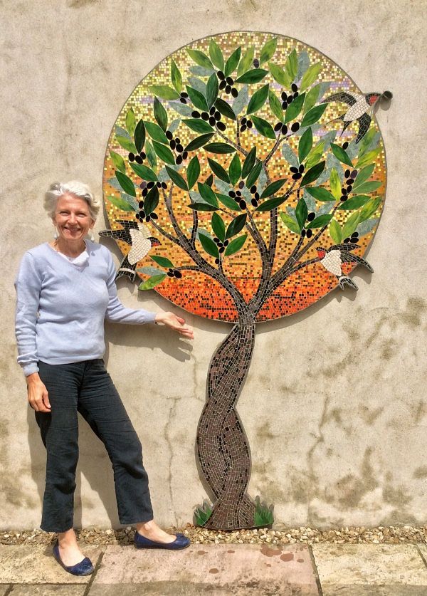 a woman standing in front of a wall with a tree on it