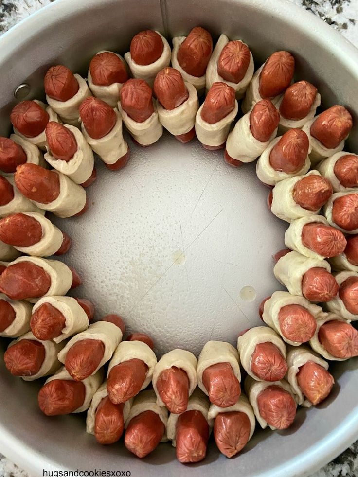 a white bowl filled with hot dogs covered in sauce