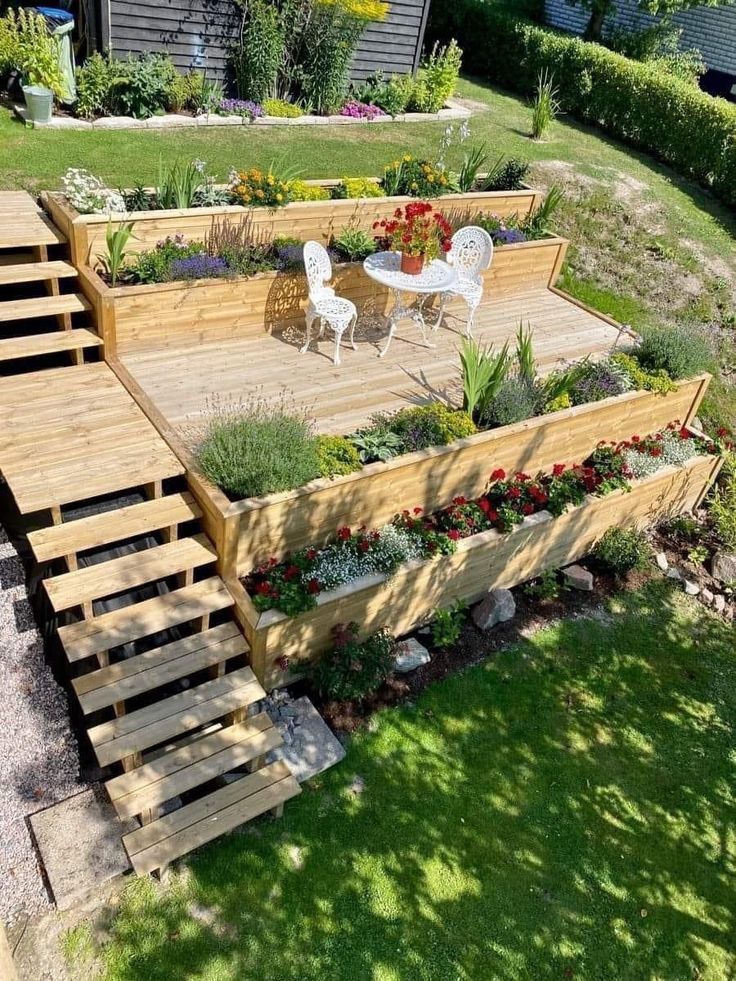 a wooden deck surrounded by plants and flowers