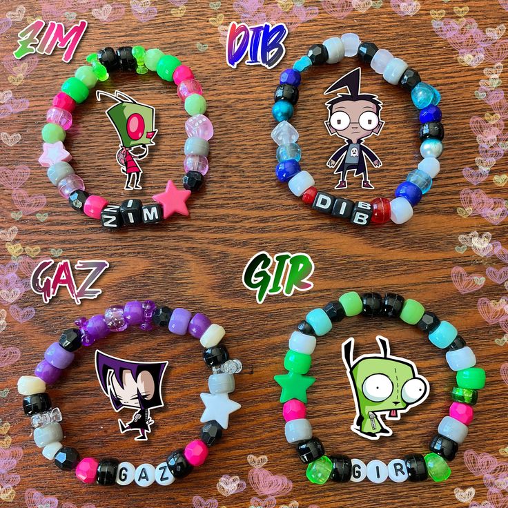 four bracelets with cartoon characters on them sitting on top of a wooden table next to stickers