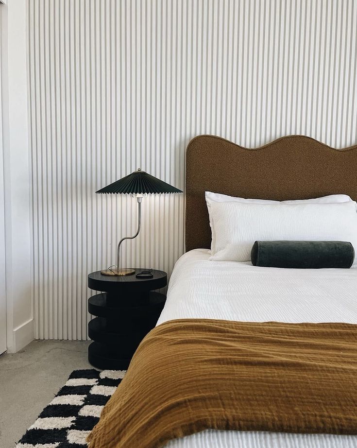 a bed sitting next to a lamp on top of a table