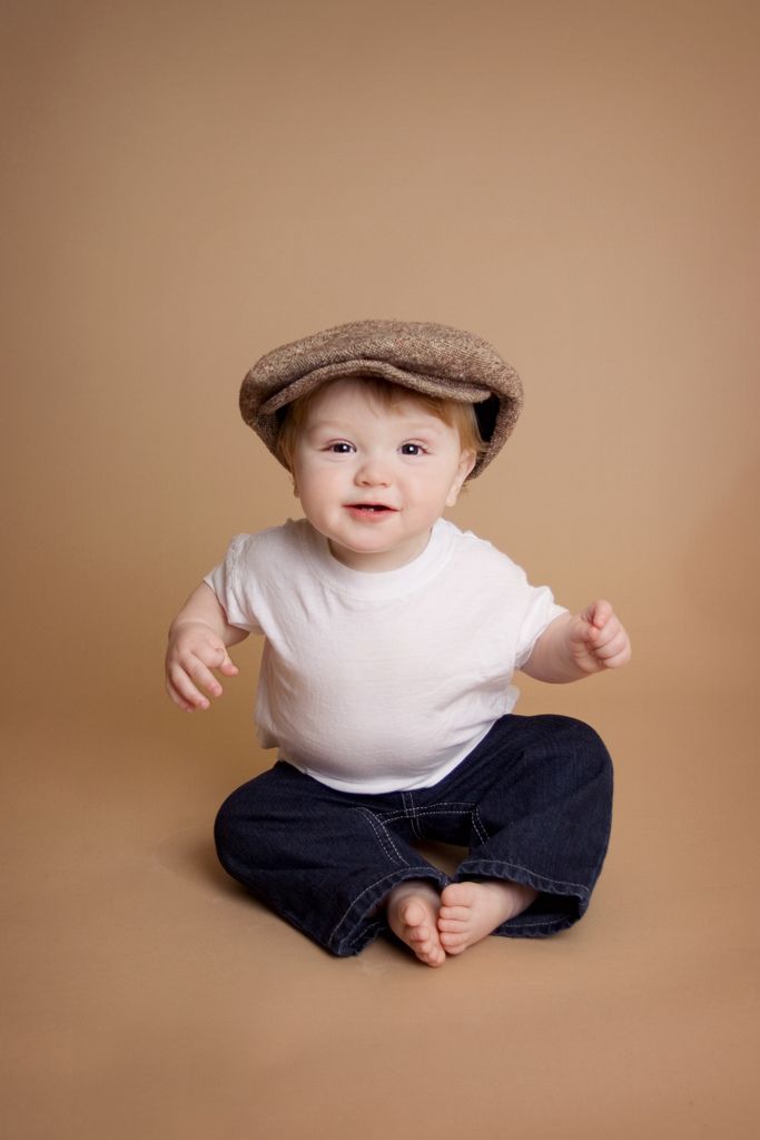 a baby sitting on the ground wearing a hat