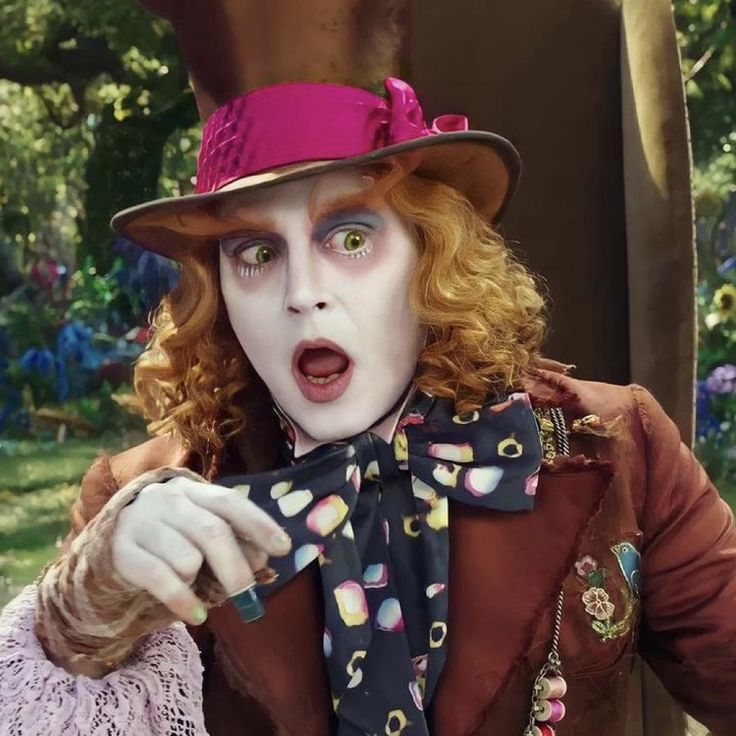 a man dressed as the mad hatter holding something in his hand and pointing at it