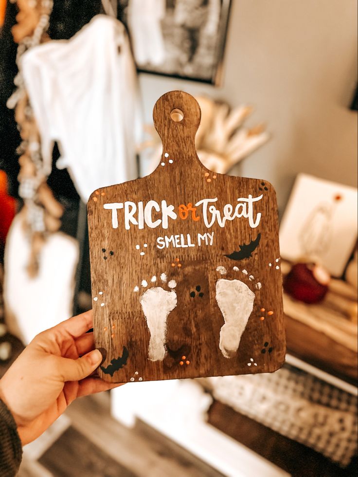 a person holding up a wooden sign that says trick or treat smell my feet on it