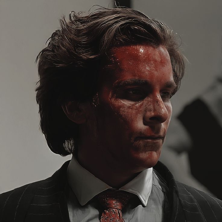 a man wearing a suit and tie with red paint on his face