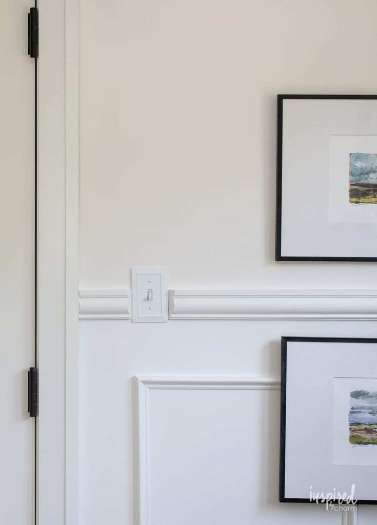 two framed pictures hang on the wall next to a door with a light switch in it