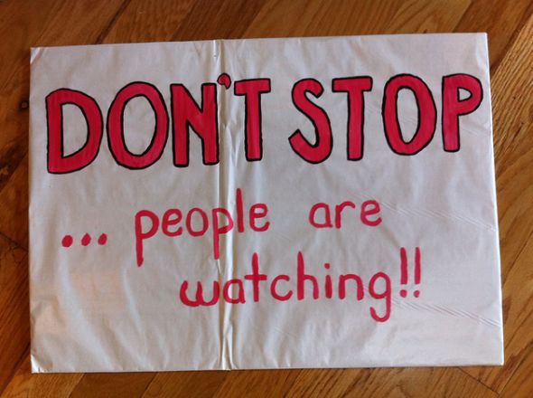 a sign that says don't stop people are watching on the floor in front of a wooden floor