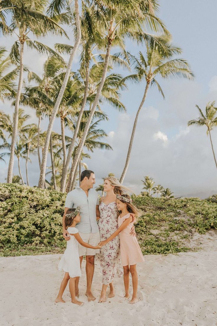 a family standing on the beach with palm trees in the background