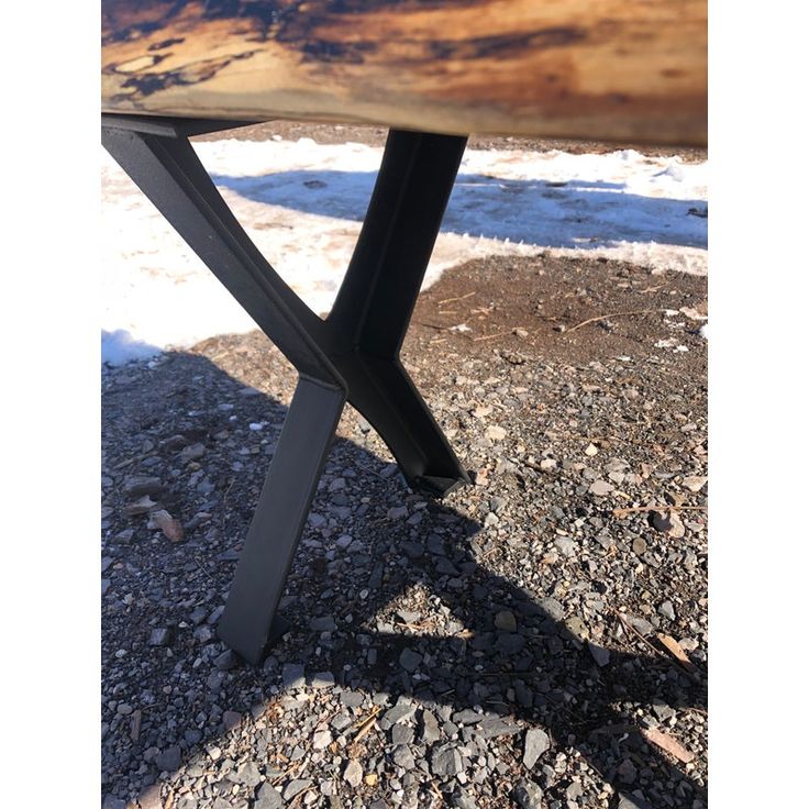 a wooden bench sitting on top of gravel covered ground