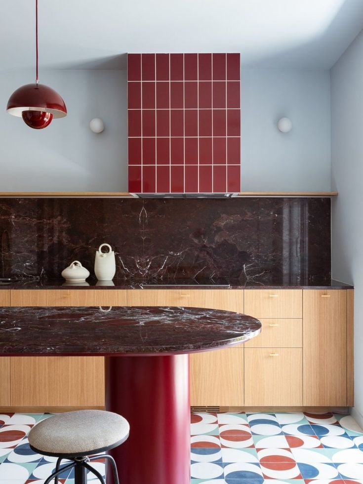 a table and stools in a room with tile flooring on the wall behind it