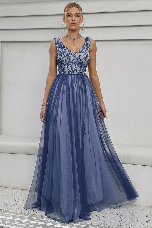 a woman standing in front of a white wall wearing a blue dress with sheer detailing