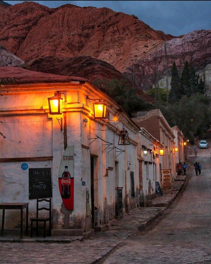 a row of white buildings with mountains in the background