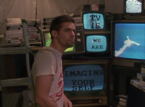 a man standing in front of televisions with words on them