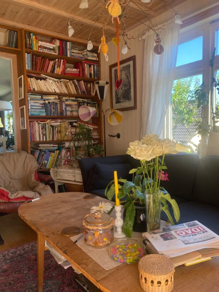 a living room filled with furniture and a book shelf full of books next to a window