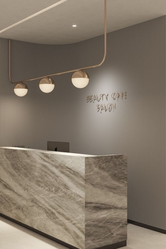 the front desk of a beauty salon with marble counter top and lights hanging from the ceiling