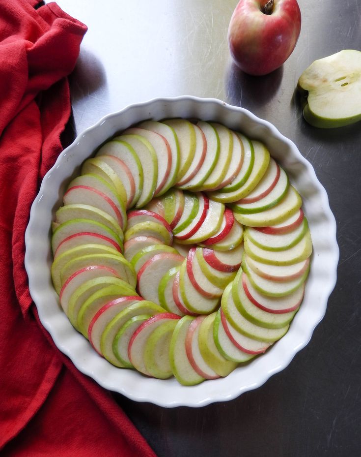 sliced apples in a pie dish on a table