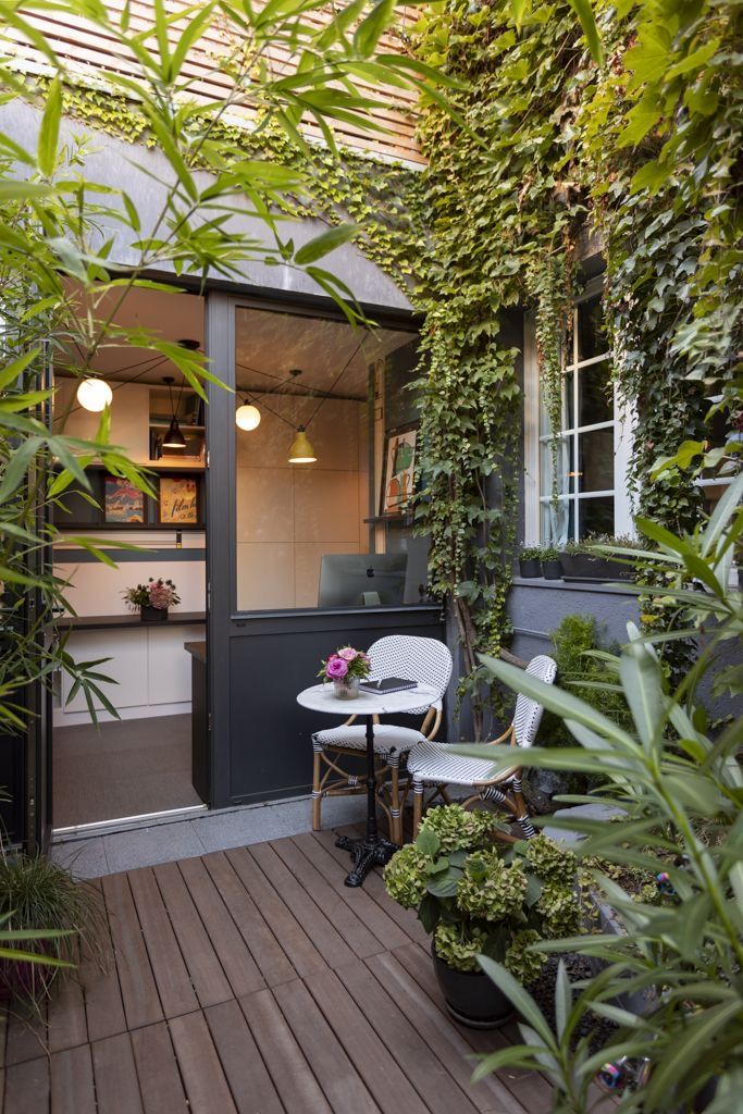 an outdoor patio with potted plants on the side and a small table in front