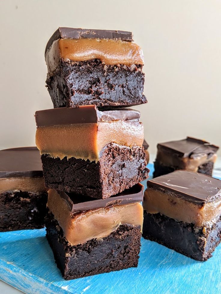 a stack of brownies sitting on top of a blue cutting board