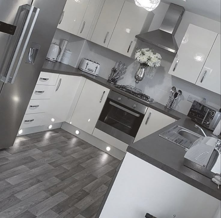 a kitchen with stainless steel appliances and white cabinets is shown in black and white colors