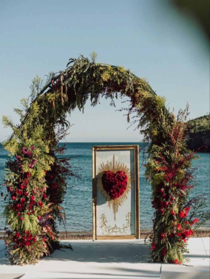 an outdoor ceremony setup with flowers and greenery on the side of the aisle, overlooking the ocean