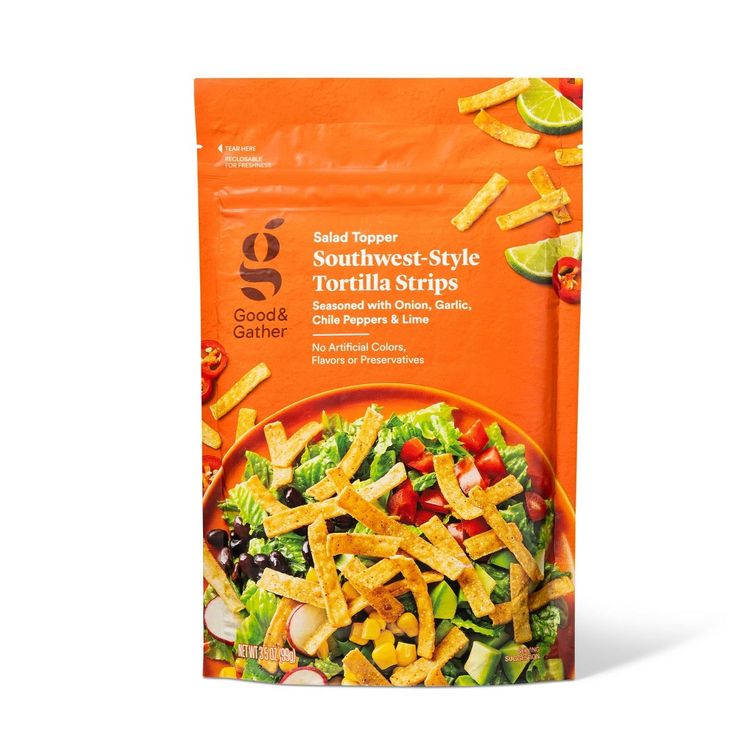 a bag of salad with tortilla strips in it on a white surface next to an orange background