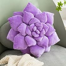 a purple flower pillow sitting on top of a gray couch next to a white glove