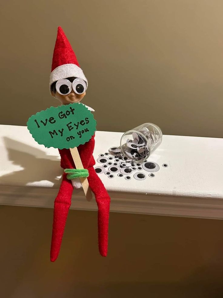 an elf is holding a sign that says i've got my eyes on you