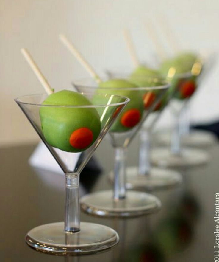 four martini glasses with green olives in them