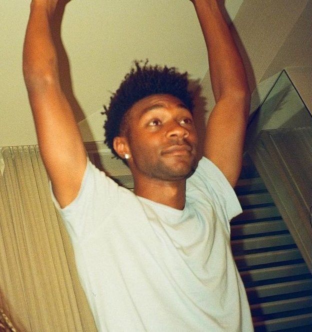 a young man is holding his hands up in the air while standing next to a stair case