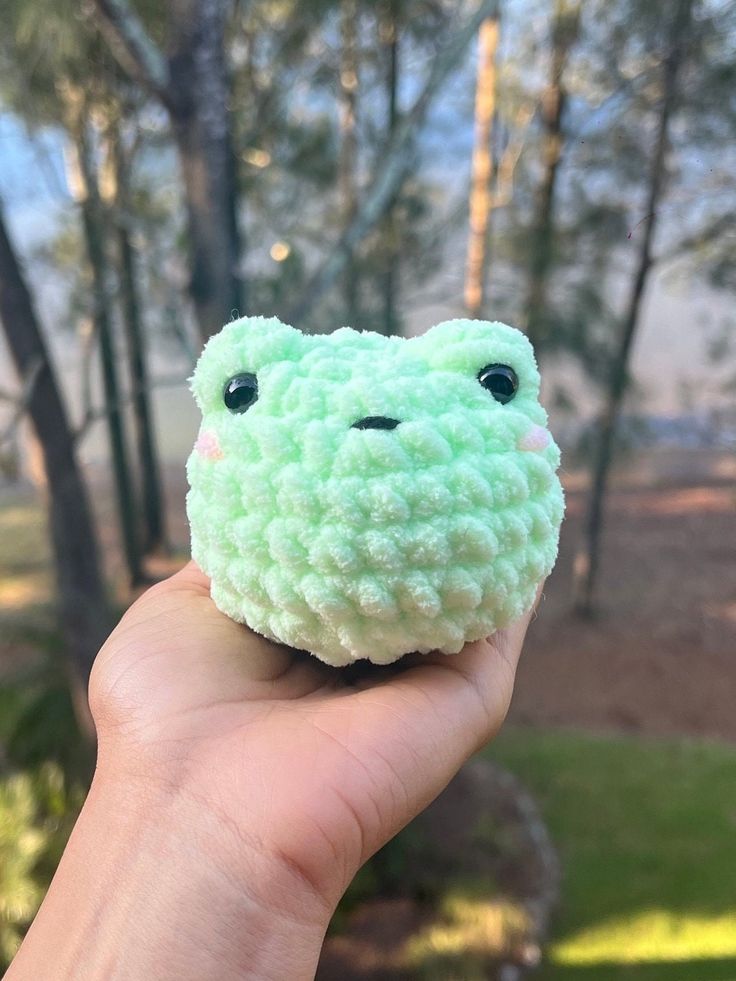 a hand holding a small green stuffed animal