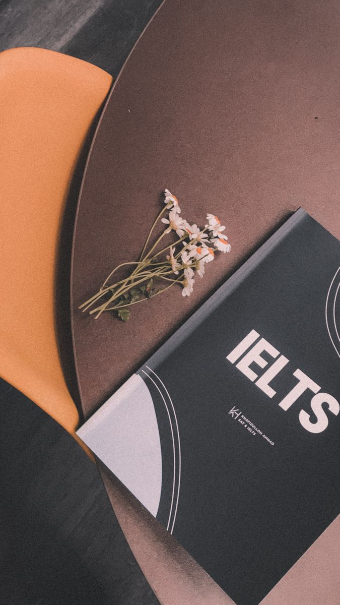 a book sitting on top of a wooden table next to a flower pot and orange chair