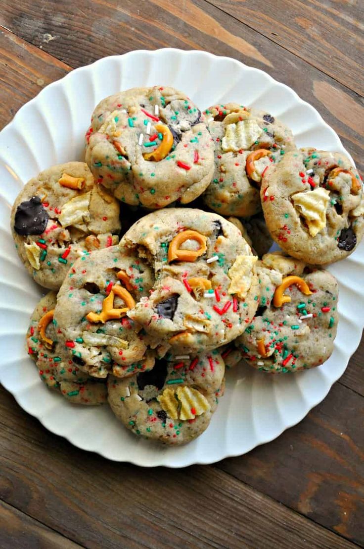 a white plate topped with cookies covered in frosting and sprinkles on top of a wooden table