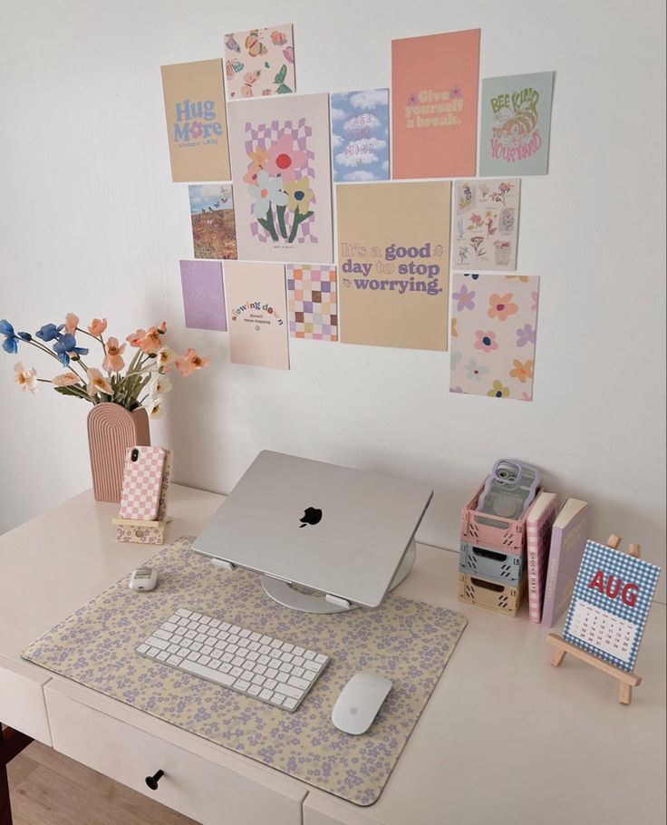 an apple computer sitting on top of a white desk next to a vase with flowers