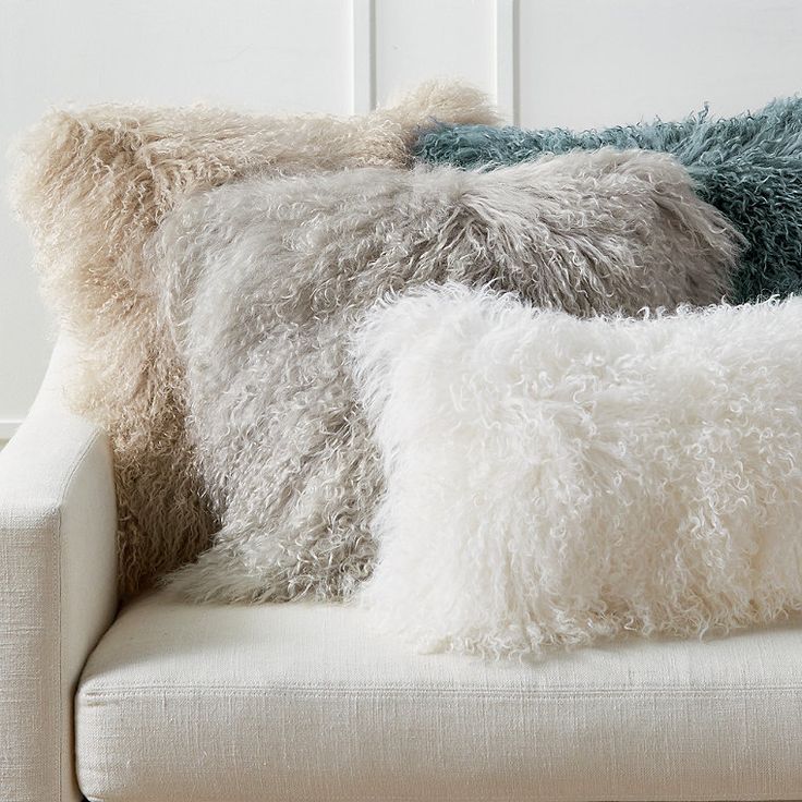 three pillows are sitting on a white couch