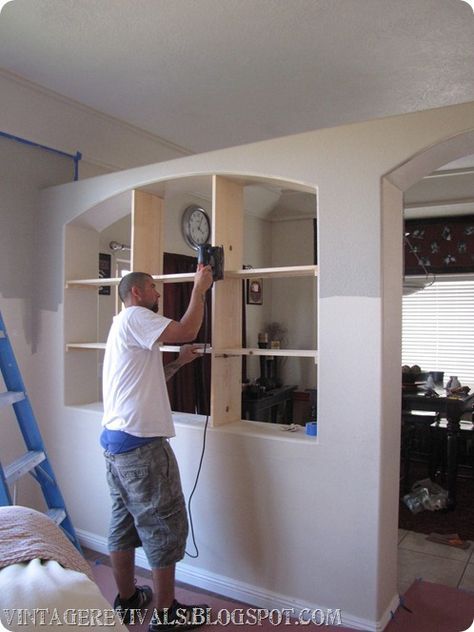 a man is working on a bookcase in the middle of a room with ladders