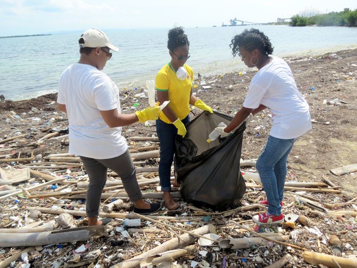 three people picking up trash on the beach