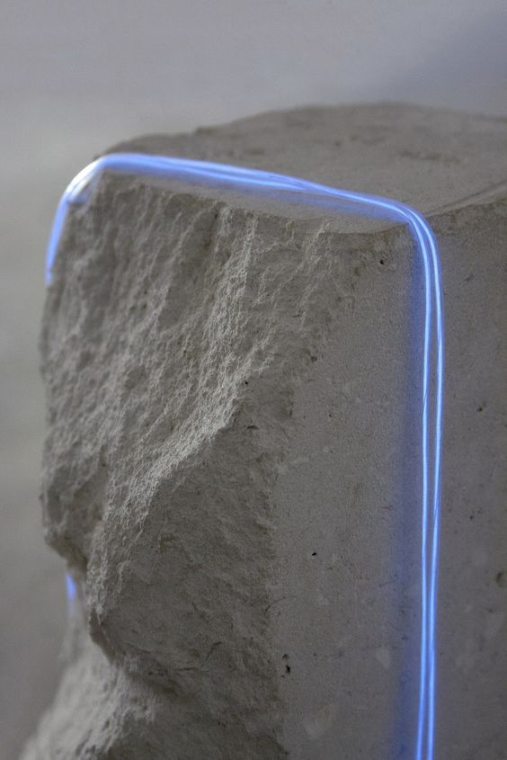 a stone block with blue neon lights on the top and bottom edge, in front of a white background