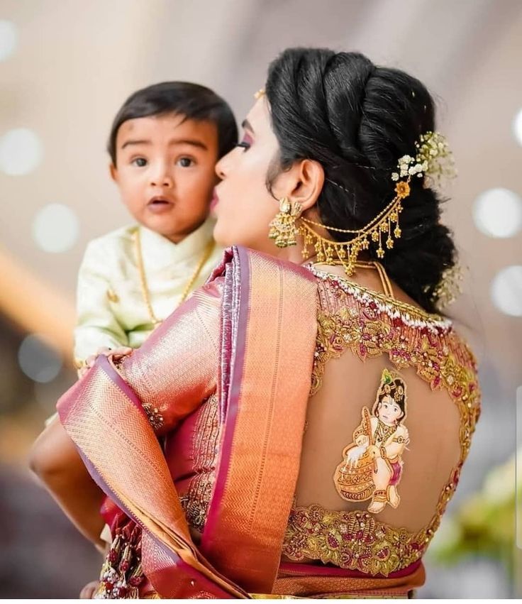 a woman holding a child in her arms and wearing a sari on top of her back