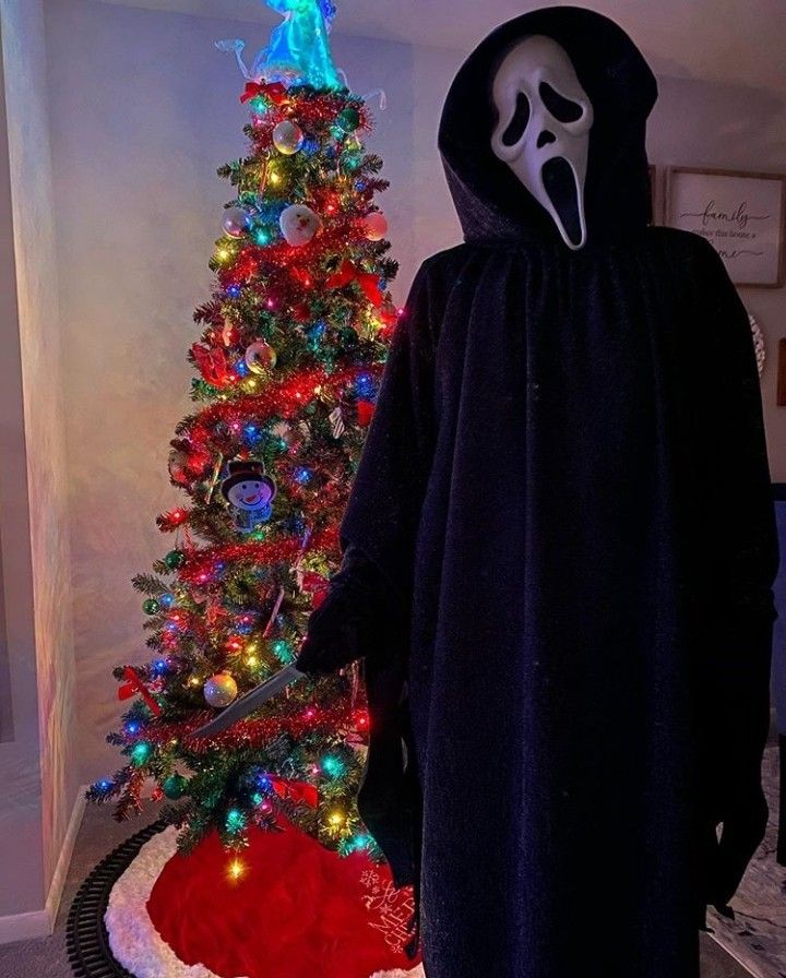 a person in a costume standing next to a christmas tree