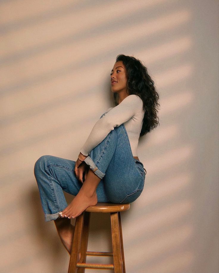 a woman sitting on top of a wooden stool