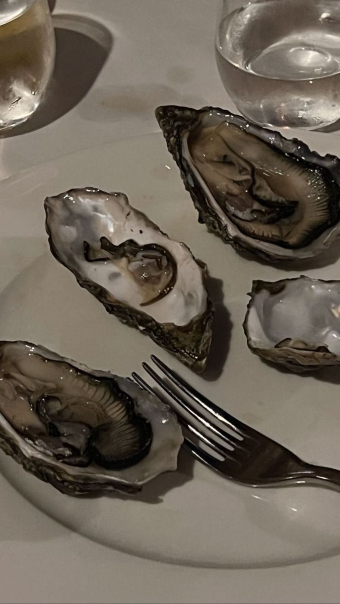 three oysters on a white plate with silverware