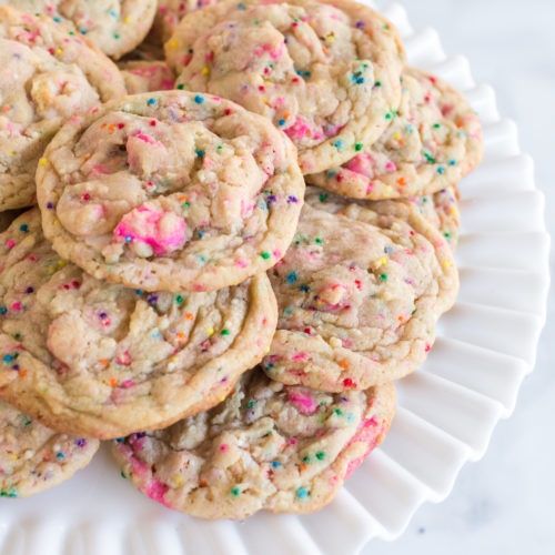 sprinkled cookies on a white plate with pink and green sprinkles