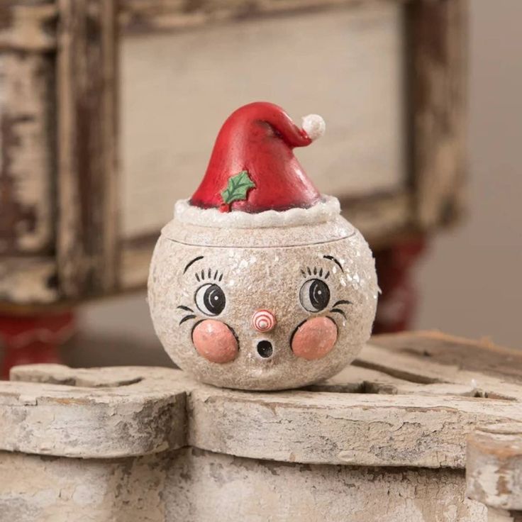 a clay pot with a face painted on it and a santa hat sitting on top of it