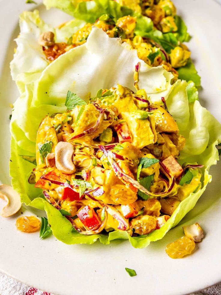 two lettuce wraps filled with different types of food on top of a white plate