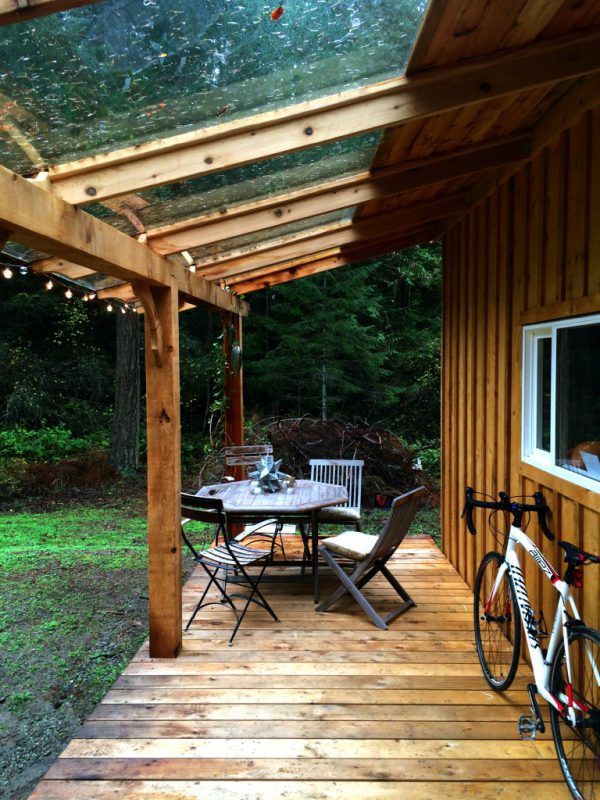 a wooden deck with chairs and table next to a bike parked on the side of it