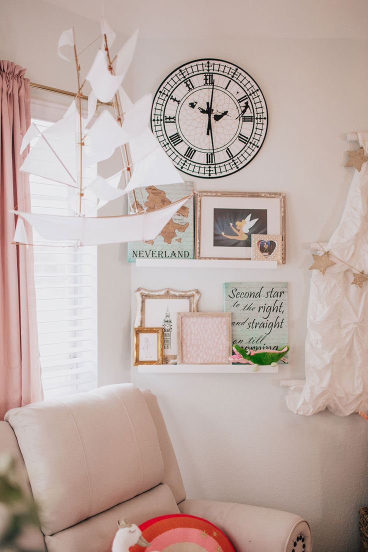 a living room with a clock on the wall and pictures hanging from the ceiling above it