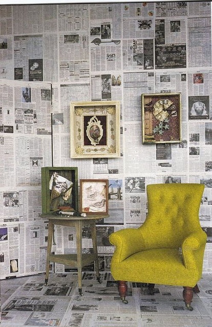 a yellow chair sitting in front of a wall covered with newspaper paper and pictures on it